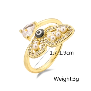 Detail of gold butterfly ring featuring pearl wings and a devil's eye gemstone
