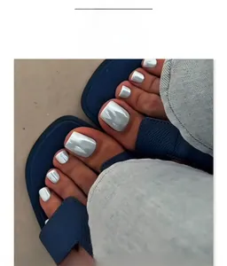 Détail de faux ongles de pieds blanc nacré avec fini métallisé portés avec sandales bleues