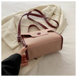 Detailed close-up of lychee textured leather and stitching on a contrast color square bag