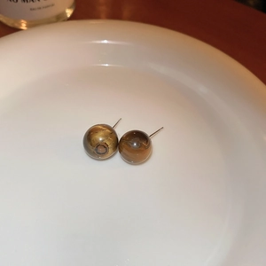 Vintage irregular tiger eye stone stud earrings with silver needles on ceramic plate