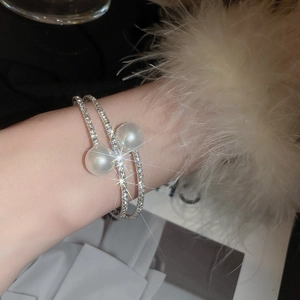 Dettaglio macro del bracciale argento con pavé di strass e due grandi perle bianche