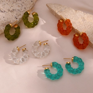 Détail de boucles d'oreilles torsadées en acrylique aux couleurs translucides et métal doré