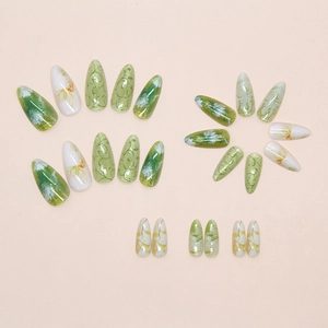 Close-up of almond press on nails with green cat-eye bubble floral and vine patterns