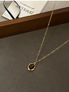 Close-up of vintage oval tiger eye stone pendant with golden edge on fine chain