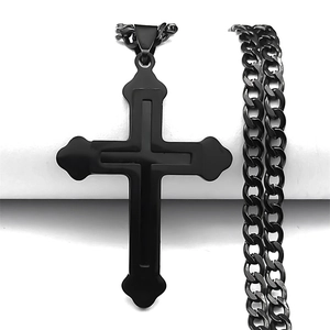 Détail d'un pendentif croix double couche en acier noir avec une chaîne cubaine