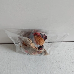 Detail of resin Santa Claus doll with red plaid outfit in clear plastic packaging