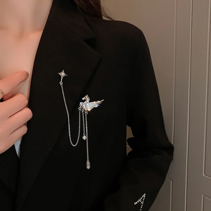 Silver Pegasus brooch with layered chains and sparkling rhinestones on a black suit lapel