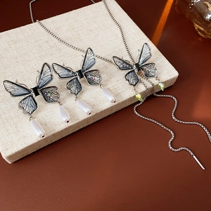 Detailed shot of butterfly pendant necklace and drop earrings with blue glitter wings