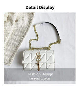 Detail of white quilted crossbody bag featuring a gold S-logo and metal tassel fringe