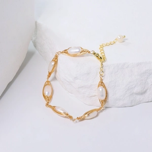 Handmade gold wire-wrapped pearl bracelet featuring white floral-style winding on white rock