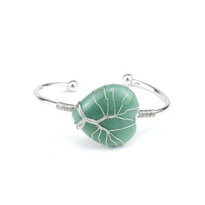Macro view of handmade silver wire wrapped Tree of Life pattern on green heart crystal