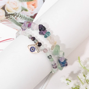 Double-layer natural irregular stone bracelet with Evil Eye charm on a white pedestal