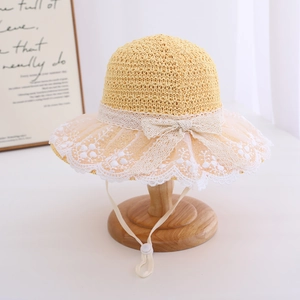 Detailed view of beige straw sun hat with white embroidery lace brim and bow