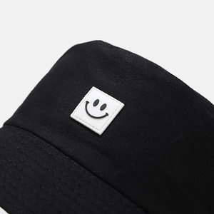 Detail of a black cotton canvas bucket hat showing the smile patch and stitched brim