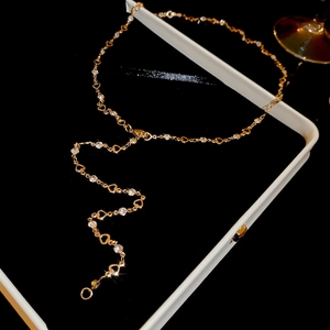 Macro shot of long gold tassel necklace featuring hollow heart motifs and shimmering crystals