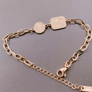 Detail of rose gold stainless steel bracelet with Lucky disk and square rabbit charms