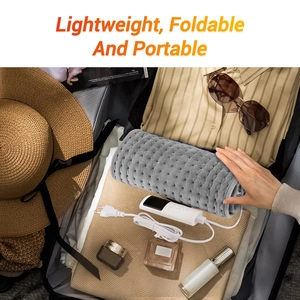 Foldable and portable grey heating pad shown inside a travel suitcase for easy transport
