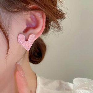 Detailed view of pink heart earrings with unique wrinkled texture and glossy enamel finish