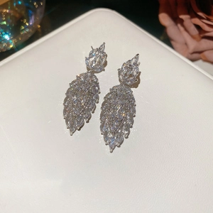 Macro shot of silver leaf-shaped earrings featuring marquise-cut zircon stones in jewelry box