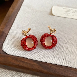 Close-up view of elegant red apple-shaped resin earrings with gold leaf accents