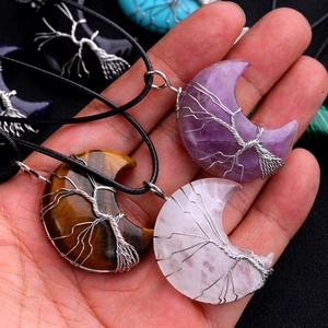 Close-up of tree of life moon pendants crafted with amethyst and natural crystal stones