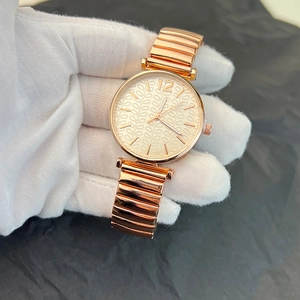 Close-up of rose gold watch with leaf texture dial and metallic segment strap