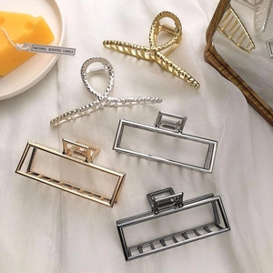 Detailed view of metal claw clips in gold, silver, and grey finishes on white fabric