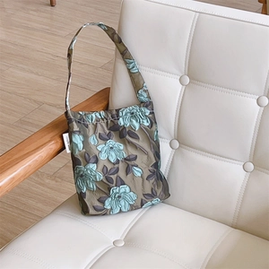 Dettaglio del tessuto jacquard vintage con ricamo floreale su borsa a mano