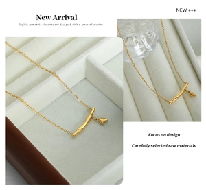 Détail d'un collier en acier titane doré avec pendentif tige de bambou et feuille ciselée