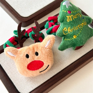 Close-up of plush reindeer and Christmas tree hair scrunchies with embroidered text