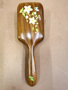 Detail of hand-painted floral pattern and butterfly on polished sandalwood massage hairbrush