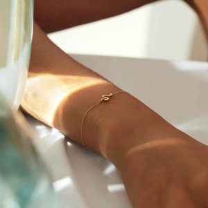 Detail of minimalist gold snake bracelet with fine scales texture on a woman wrist