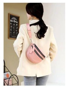 Close-up of pink PU leather multi-zipper dumpling bag on a model wearing a beige blazer