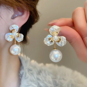 Detailed close-up of a luxury gold-plated flower earring with white petal pearls