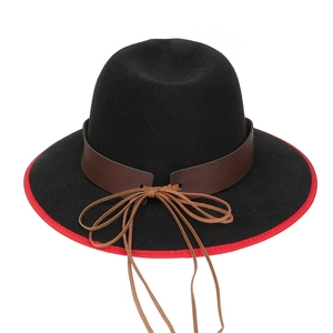 Detail view of the black felt hat featuring a bold red brim and vintage leather strap