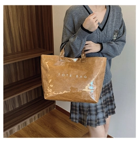 Waterproof brown Tyvek tote bag with white text held by a model in an indoor setting