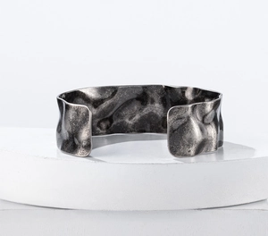Macro detail of wide open cuff bracelet featuring antique silver hammered lava texture