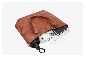 Spacious brown leather tote bag interior showing capacity for umbrella, phone and notebook