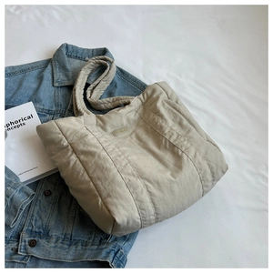 Detailed view of beige quilted nylon tote bag with wide shoulder strap and soft texture