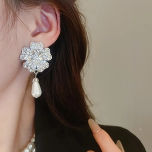 Close-up of silver flower earrings with sparkling rhinestones and a pear-shaped pearl drop