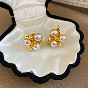 Macro shot of French vintage gold flower earrings with white pearls in a silk shell box