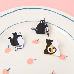 Lot de trois pin's en émail avec des chats rigolos présentés sur une assiette décorative