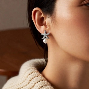 Close-up of star pearl earring with zircon inlays worn on ear with soft lighting