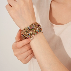 Détail d'un bracelet multicouche en perles de bronze et couleurs sur un poignet féminin