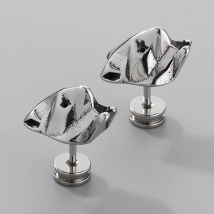 Macro shot of silver titanium steel earrings with irregular wrinkled texture and industrial style