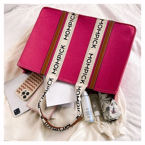 Flat lay of pink felt tote bag organized with tablets and daily essentials on white cloth