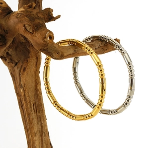 Gros plan de bracelets perlés en acier titane doré et argenté sur support en bois