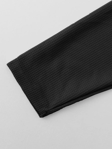 Macro shot of black waffle knit fabric showing premium texture and ribbed hem detail
