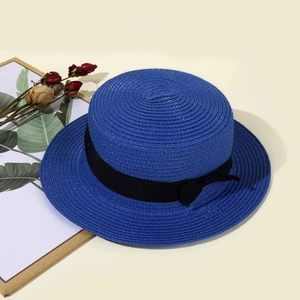 Close-up of the woven texture and black ribbon bow on the royal blue straw boater hat
