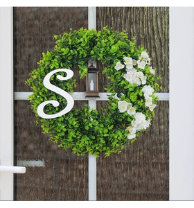 Detail of Christmas wreath with eucalyptus, white flowers, lantern and letter S on a glass door